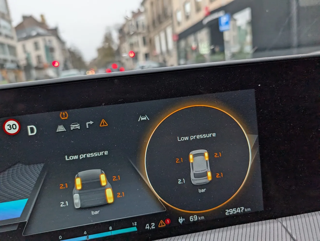 Car dashboard showing TPMS Low Pressure warning with tire readings at 2.4-2.5 bar
